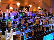 Back bar with midnight blue lighting. It has a stylish feel.